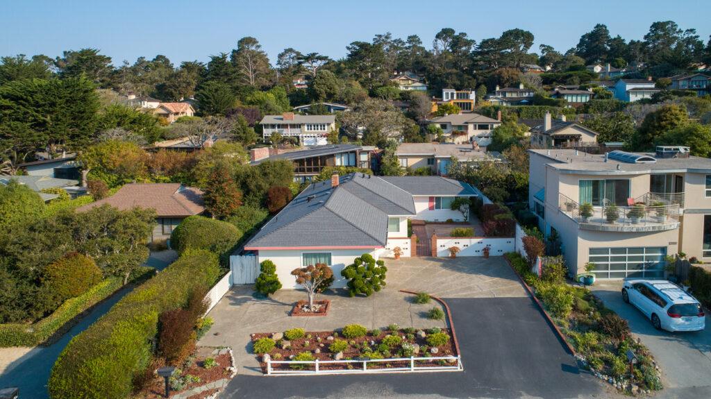 Aerial view of Carmel home before remodel showing large concrete driveway with minimal outdoor living space