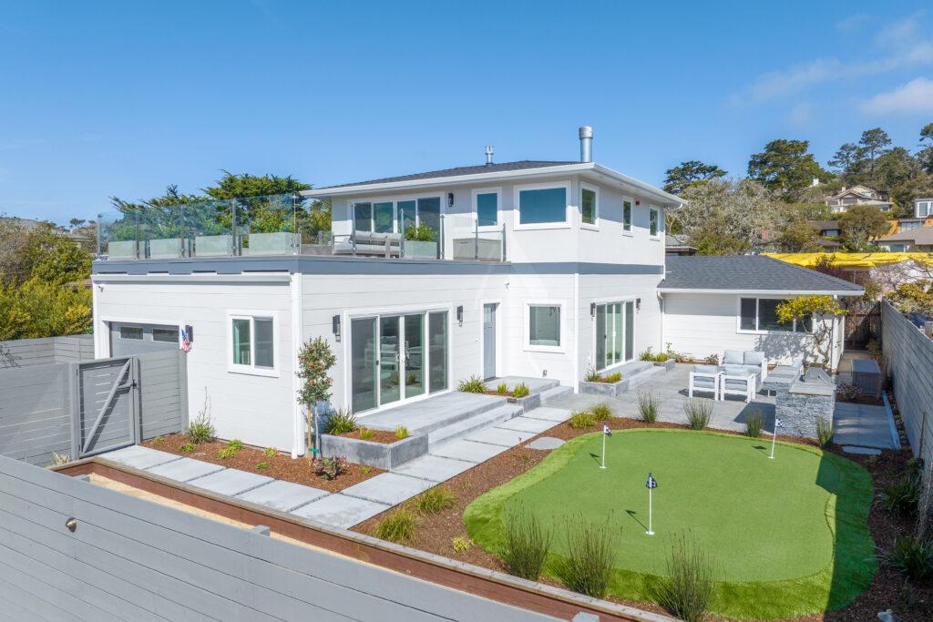 Aerial view of remodeled Carmel home with putting green, patio, and second-story view deck